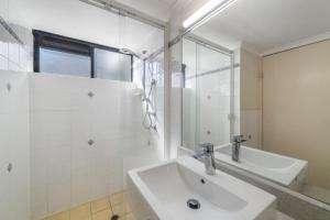 un bagno bianco con lavandino e doccia di Windward 4, 3 bedroom unit ocean front a Mooloolaba