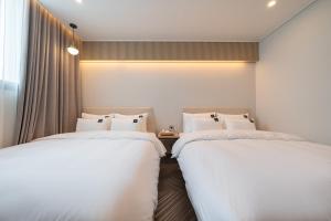 two beds sitting next to each other in a room at Browndot Gangneung Station in Gangneung