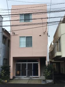 een roze gebouw met veel ramen bij Accommodation Service B&B in Miyazaki