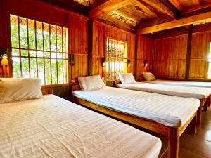 2 Betten in einem Zimmer mit Holzwänden und Fenstern in der Unterkunft Dao Homestay in Hoàng Su Phì