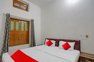 a bedroom with a bed with red and white pillows at OYO Flagship J.d.p Guest House in Varanasi