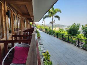 a porch of a building with wooden benches and a sidewalk at Suksomboonhotel in Loei