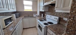a kitchen with a white stove top oven next to a sink at Seaview Property 3B Two Bedroom Apt Hasting Towers in Bridgetown
