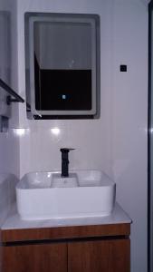 lavabo en el baño con TV en la pared en Lujoso y Moderno Departamento Stadium, en Cochabamba