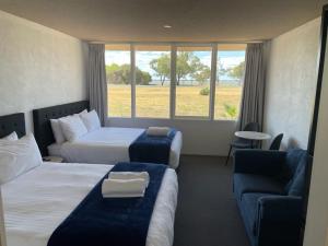 une chambre d'hôtel avec deux lits et un canapé dans l'établissement Happy Wanderer Motel Lake Boga ON THE LAKE WITH LAKE VIEWS, à Lake Boga