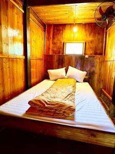 ein großes Bett in einem Zimmer mit Holzwänden in der Unterkunft Dao Homestay in Hoàng Su Phì
