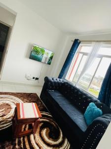 sala de estar con sofá negro y ventana en Omuts one bed airbnb with swimmingpool en Kiambu