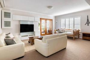 a living room with white furniture and a flat screen tv at NEW! Modern, Cozy 2BR Home Away from Home w/ Wifi in Perth