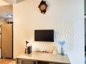 a tv on a wall with a clock and a desk at Klang Prima Bayu Cozy 4-Room Retreat in Klang