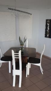 mesa de comedor con 2 sillas blancas y mesa de cristal en Habitación de Soltero, en Panamá