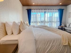 a bedroom with a large white bed with blue curtains at CRAFT 7th Boutique Nimman in Chiang Mai