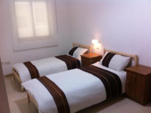two beds in a hotel room with a light on at Genista Apartment in Kalkara