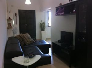 a living room with a black leather couch and a table at Genista Apartment in Kalkara