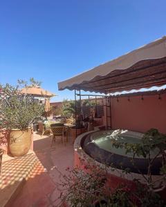 um pátio com uma banheira de hidromassagem e um guarda-sol em Dar Al Assad em Marrakech