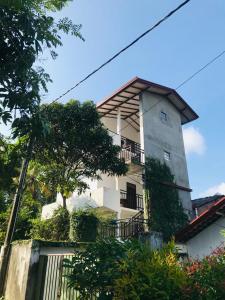 a tall white building with a balcony at Sun Shine House in Matara