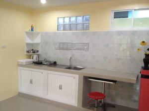 a kitchen with a sink and a red stool at Kathu Waterfall Bungalow in Kathu