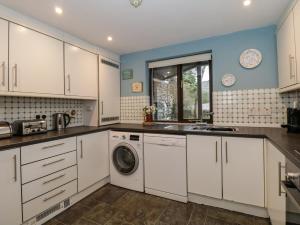 a kitchen with white cabinets and a washer and dryer at Gillybeck in Ambleside