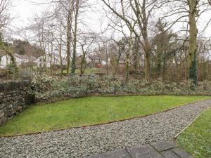 a garden with a stone wall and green grass at Gillybeck in Ambleside