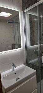La salle de bains est pourvue d'un lavabo, d'une douche et d'un miroir. dans l'établissement Willa Samana Pokoje, à Dziwnówek