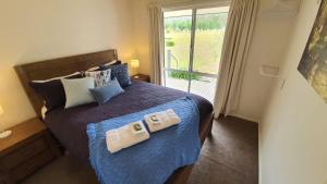 Un dormitorio con una cama con dos almohadas y una ventana. en Feathertop Views and Barn, en Wandiligong
