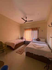 two beds in a room with a window at Hotel BhupuSainik Sauraha in Sauraha