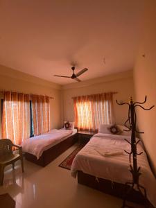 a bedroom with two beds and a ceiling fan at Hotel BhupuSainik Sauraha in Sauraha