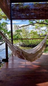 a hammock hanging from a porch next to the water at Villa Luzo in Saonek
