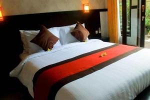 a large bed with a red and white blanket at Antara Sunset Road in Denpasar