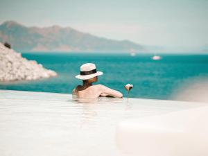 Perios Beach House - Adults Only في تورونش: رجل يرتدي قبعة في الماء مع وردة