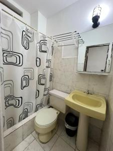 ein Badezimmer mit einem Waschbecken, einem WC und einem Duschvorhang in der Unterkunft Atlantic Suites Hotel in Guayaquil