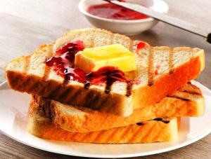 a plate with two pieces of toast with jam and butter at Kastle Guest House in New Delhi