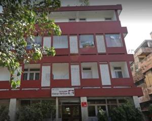 un bâtiment rouge avec un panneau devant lui dans l'établissement Kastle Guest House, à New Delhi