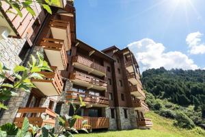 un edificio con balcones de madera en una colina en Résidence Les Sentiers du Tueda - maeva Home - 2 Pièces 4 Personnes Sélect 11, en Les Allues