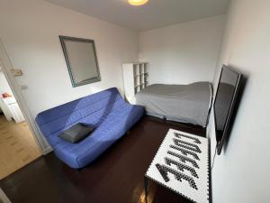 Habitación pequeña con sofá azul y cama en Logements Gare Brignoud, en Villard-Bonnot