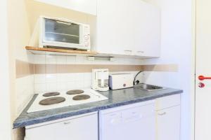 eine Küche mit einem Herd und einer Mikrowelle in der Unterkunft Résidence L'Eyssina - maeva Home - Studio 6 Personnes Budget 48 in Vars