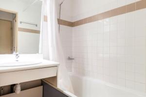 ein Badezimmer mit einem Waschbecken, einer Badewanne und einem Spiegel in der Unterkunft Résidence L'Eyssina - maeva Home - Studio 6 Personnes Budget 48 in Vars