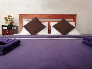 a large bed with purple sheets and pillows at Opal Cottage Ella in Ella
