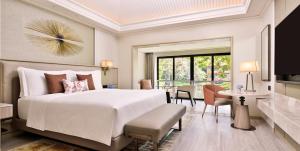 a bedroom with a large white bed and a living room at The St. Regis Goa Resort in Cavelossim