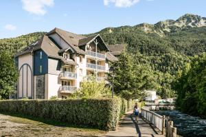 a woman walking down a path in front of a building at Résidence Les Rives de L'Aure - maeva Home - 2 Pièces 6 Personnes Sélectio 01 in Saint-Lary-Soulan