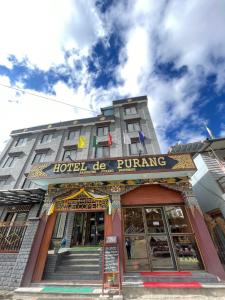 un bâtiment d'hôtel avec un panneau à l'avant dans l'établissement Hotel De Purang, à Muktināth