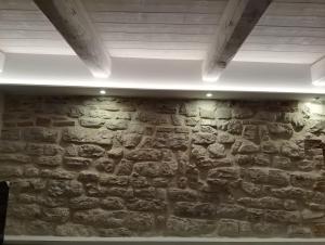 una stanza con un muro in pietra e luci sopra di Via Mazzini Home a Gubbio