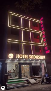 a hotel with a neon sign in front of it at Hotel Sadashiv in Ujjain