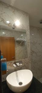 a bathroom with a white sink and a mirror at Hotel Sadashiv in Ujjain