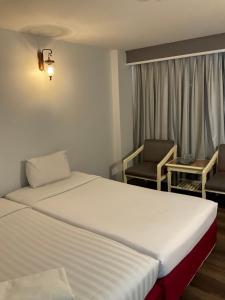 una habitación de hotel con 2 camas y una silla en INTERTOWER HOTEL (SHA) en Sungai Kolok