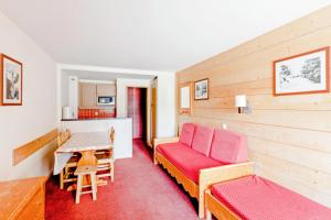 - un salon avec un canapé rouge et une table dans l'établissement Résidence Le Tikal - maeva Home - 3 Pièces 6 Personnes Budget 54, à Val Thorens