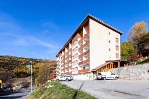 un edificio con dos coches estacionados frente a él en Appartement 6 pers. à 30m des remontées - Maeva Particuliers - 3 Pièces 6 Personnes Sélection 138716 en L'Alpe-d'Huez