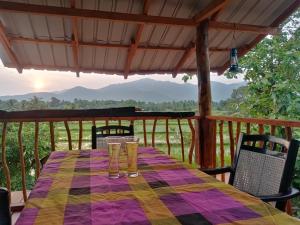 a table with glasses on a deck with mountains in the background at Ridge Boundary View in Dambulla
