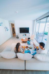 a family sitting on a couch in a living room at Avani Plus Khao Lak Resort in Khao Lak