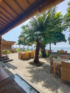 a patio with a palm tree and a table and chairs at New Starlight Hotel Lovina in Lovina