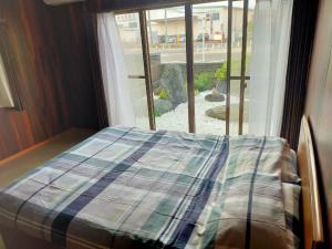 Bett vor einem Fenster in einem Zimmer in der Unterkunft 韶光民泊 in Shizuoka